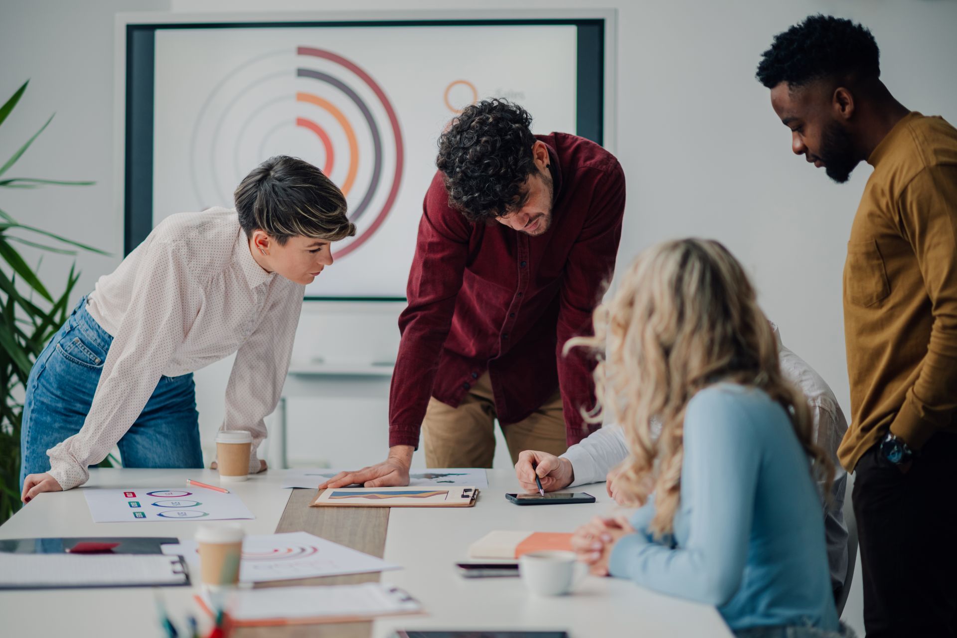 Team discussing digital workflow strategies around a table, reflecting structured support often used alongside an onlyfans agency.